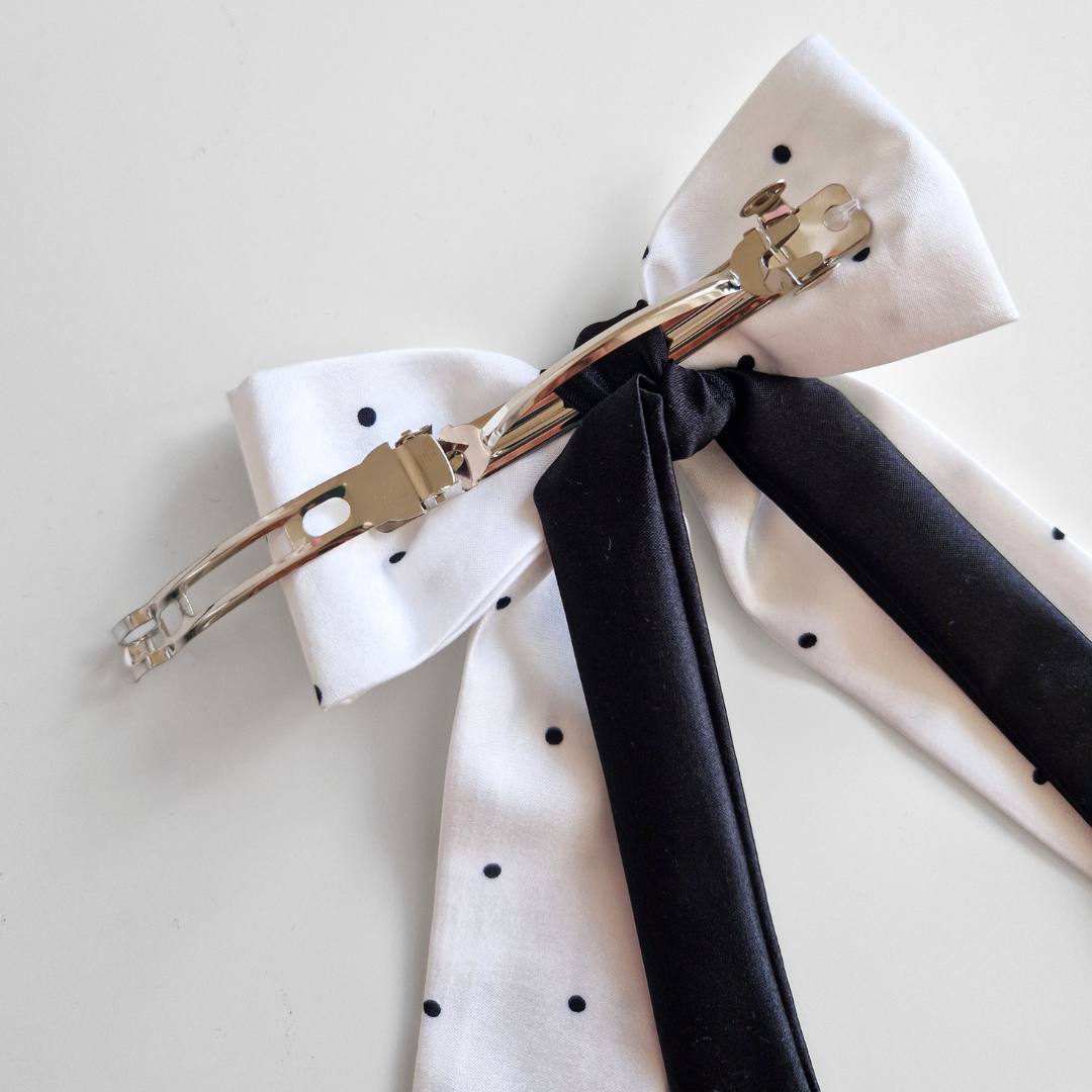 White bow tie with black ribbon on a light gray background