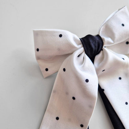 White bow with black polka dots on a light gray background